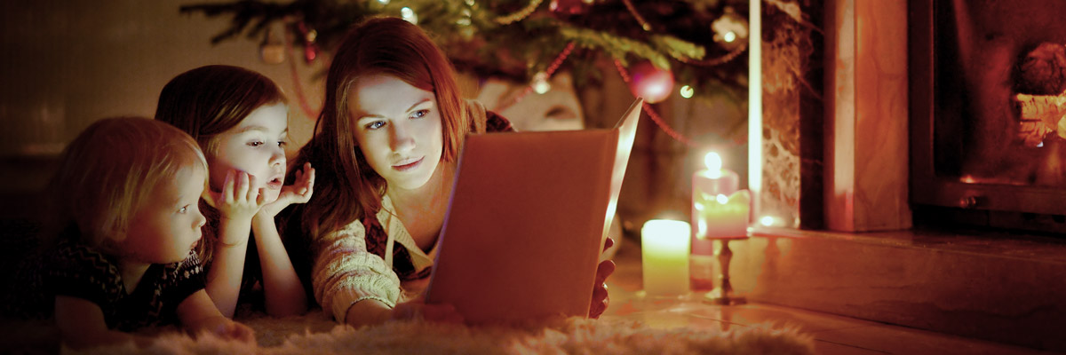 Una joven lee un libro a dos niños en Navidad